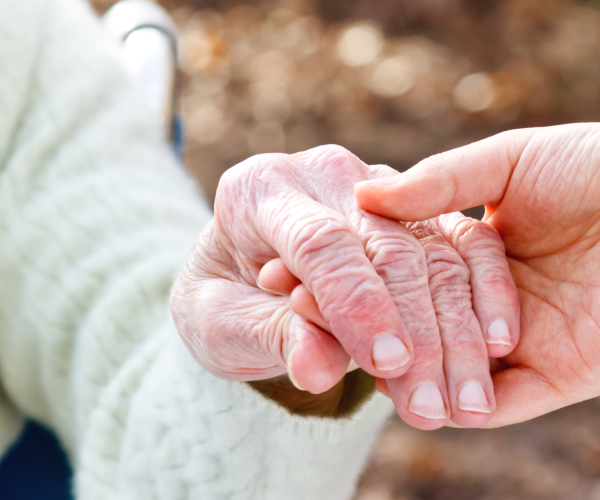 Caregiver's hand holding a senior's hand